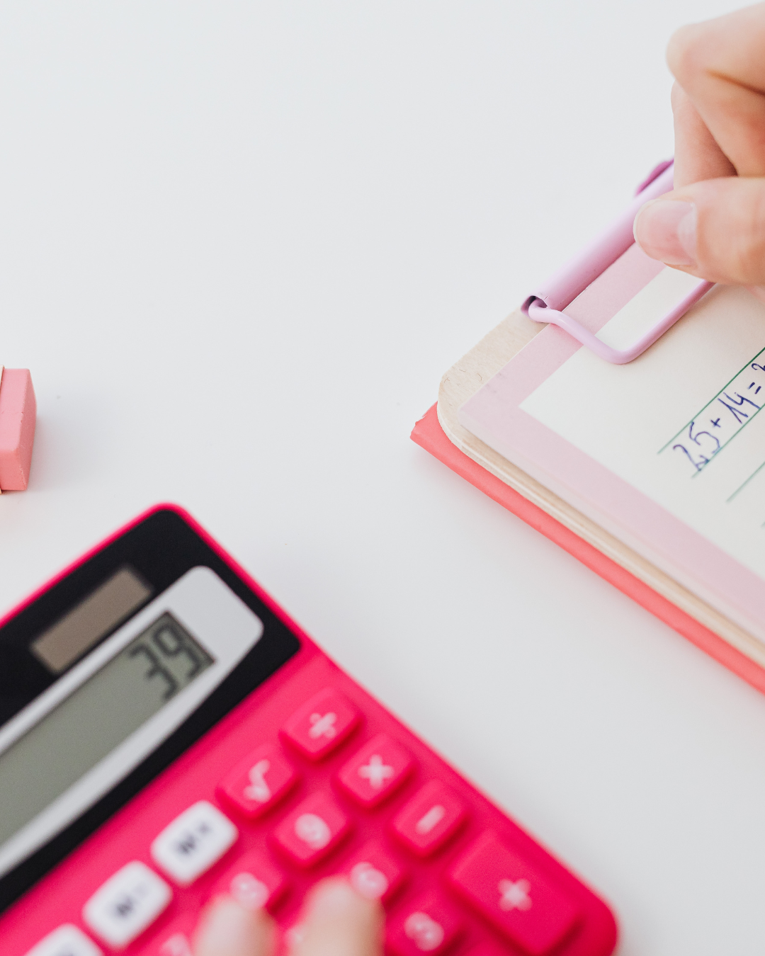 Henkilö tekemässä kuukausibudjettia kotona pöydän ääressä muistikirjan ja laskimen kanssa.